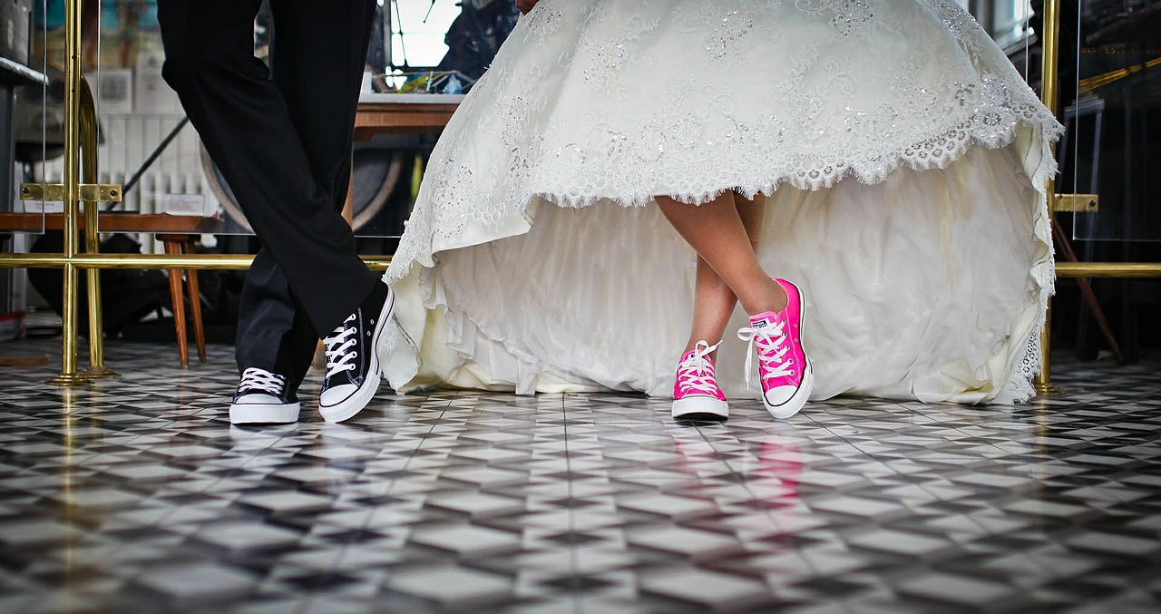 Bride and groom wearing sneakers beneath a wedding dress